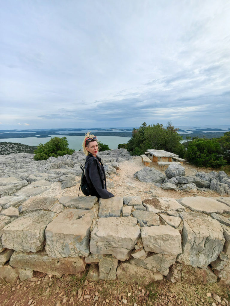 Tena na zidu vidikovca Kamenjak. Iza se vide kamene klupe na vidikovcu i u pozadini Vransko jezero i dalmatinski otoci.