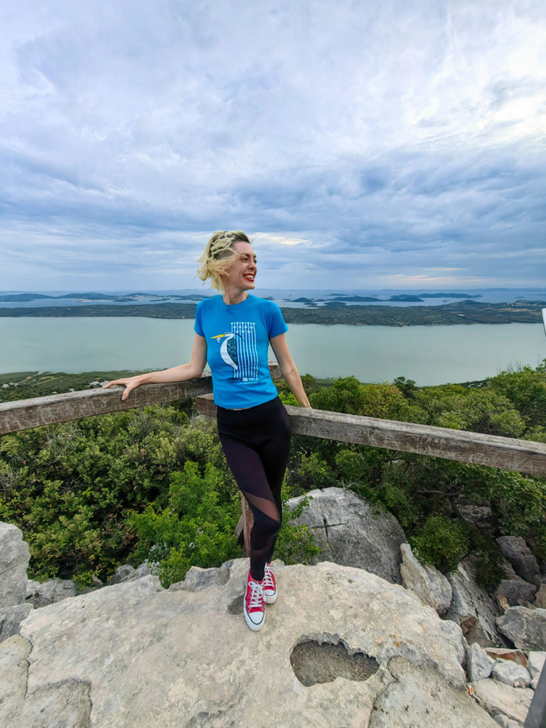 Tena na vidikovcu Kamenjak u majici s amblemom Vranskog jezera. U pozadini Vransko jezero i dalmatinski otoci.