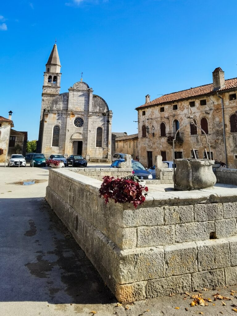 Glavni trg u Svetvinčenatu s bunarom i crkvom Navještenja Marijina u pozadini.